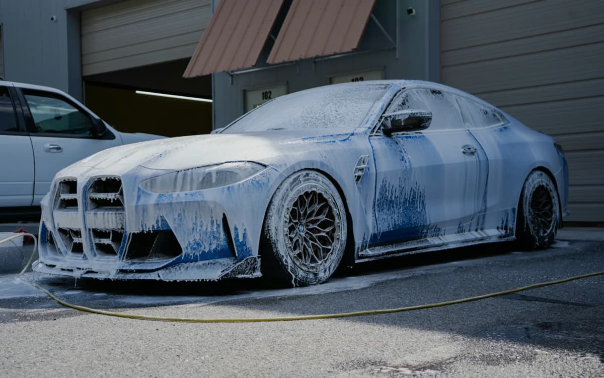 BMW M coupe covered in soap foam during a mobile exterior detail